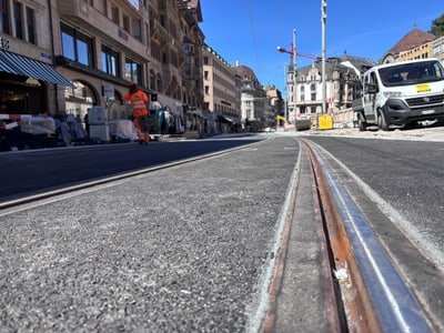 Strassenszene mit Schienen, Bauarbeiter und Fahrzeugen.