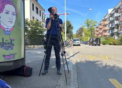 Fotograf mit Stativ auf städtischer Strasse.