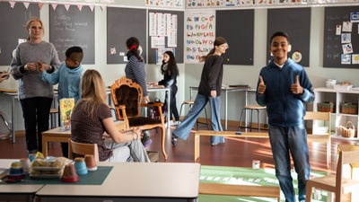 Kinder und Lehrerin in einem belebten Klassenzimmer.