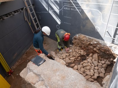 Zwei Archäologen arbeiten an alter Mauer in Baugrube.