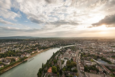 Luftaufnahme einer Stadt mit Fluss und untergehender Sonne.