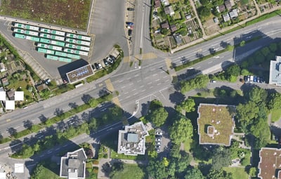 Luftaufnahme einer Kreuzung mit Bäumen und Häusern.