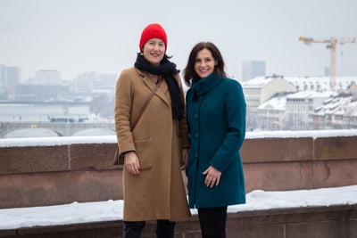 Martina Waltimo und Patrizia Porcaro in Wintermänteln vor schneebedeckter Stadtlandschaft.