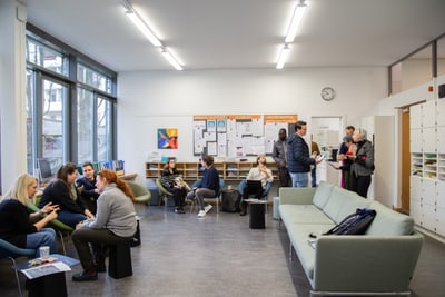 Menschen in einem Gemeinschaftsraum unterhalten sich und warten.