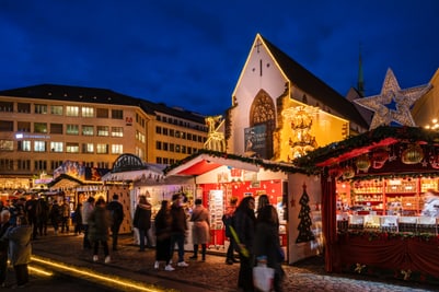 Basler Weihnachtsmarkt bei Nacht mit erleuchteten Ständen und Menschenmenge.
