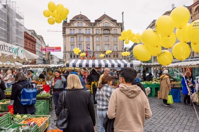 Menschen auf einem belebten Marktplatz mit gelben Ballons.
